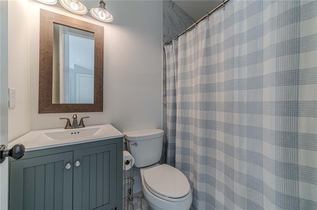 220 Audreys Way Suwanee, GA 30024 - Photo 54 of 66 a bathroom with a sink a toilet a mirror and shower curtain