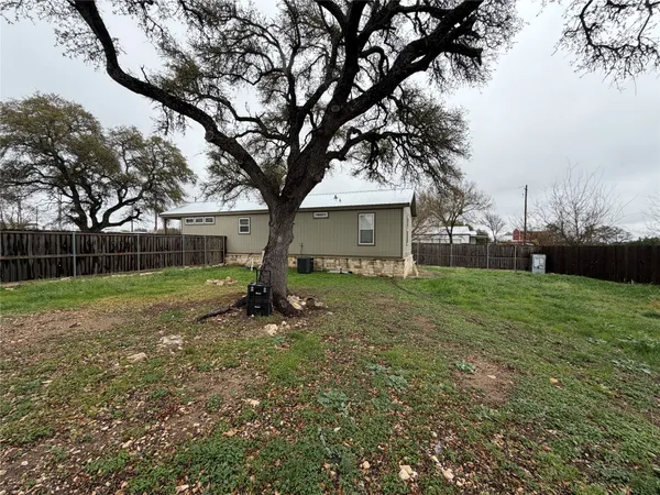a view of a house with backyard and a tree