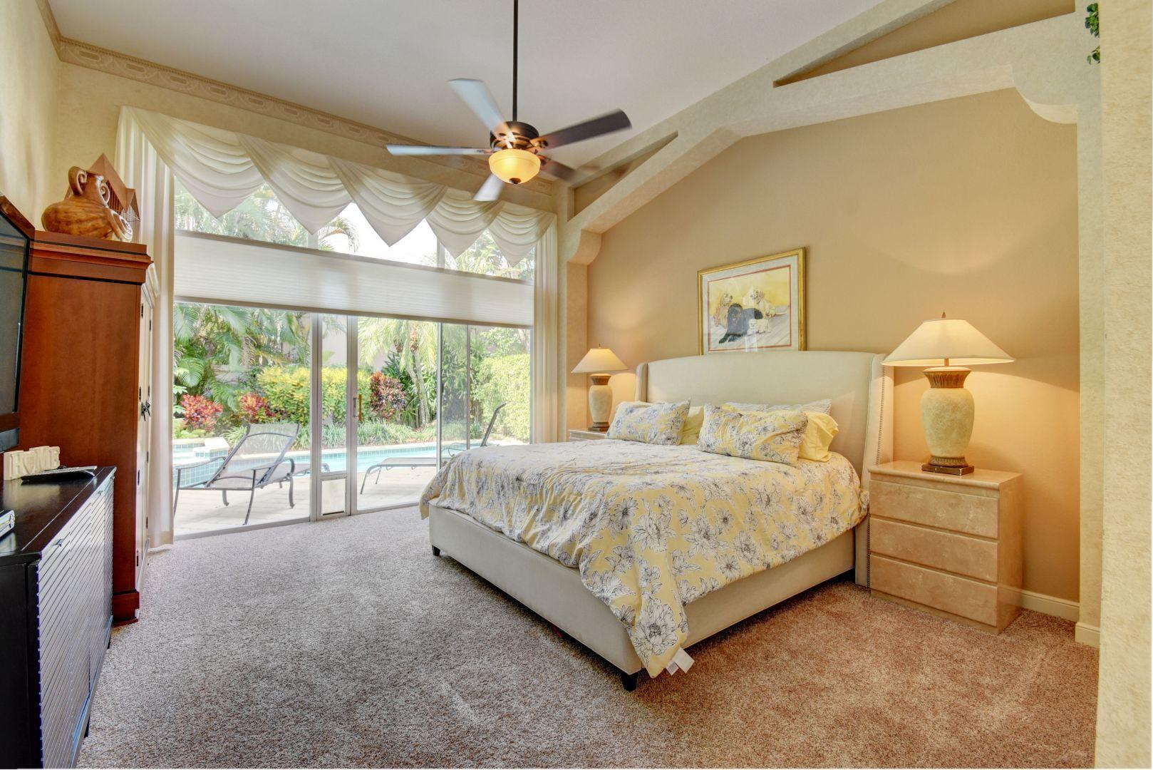 6053 Northwest 42nd Way Boca Raton, FL 33496 - Photo 16 of 23 a spacious bedroom with a bed and a chandelier