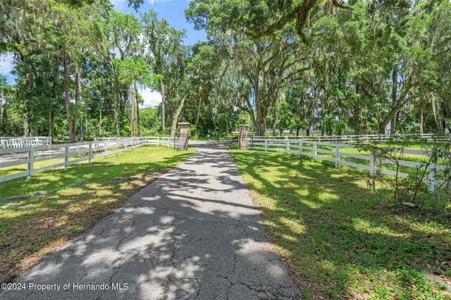 an aerial view of residential house with outdoor space and trees all around