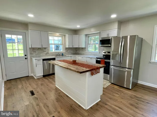 a kitchen with a sink a refrigerator a counter top space and cabinets