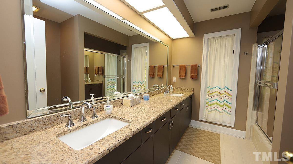 7300 Rainwater Road Raleigh, NC 27615 - Photo 12 of 18 a bathroom with a granite countertop sink a mirror and a bathtub
