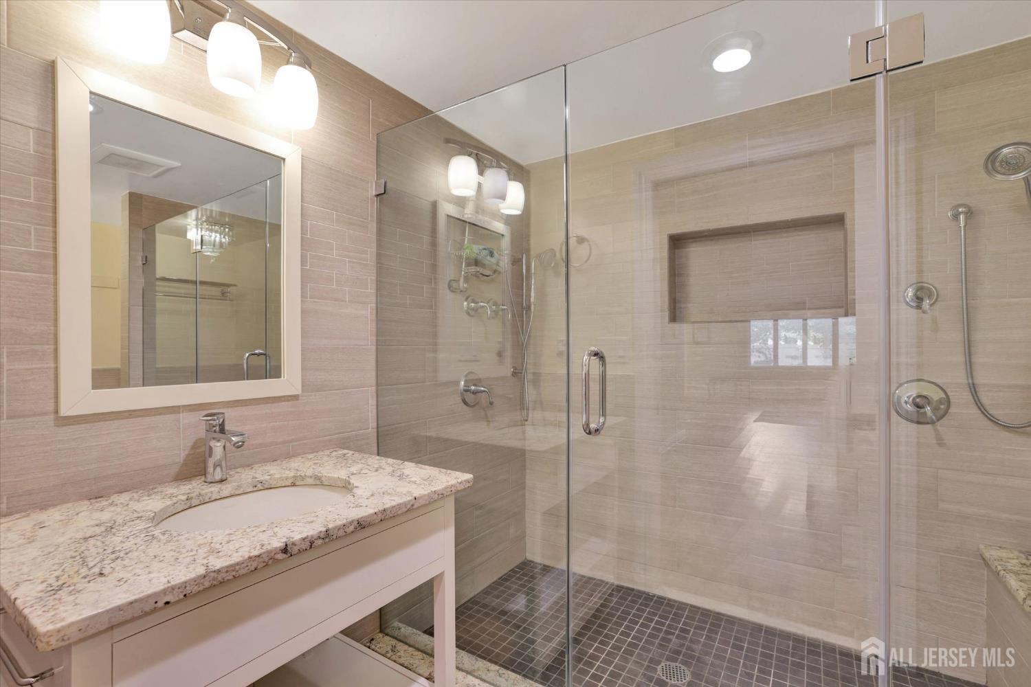 403 New Dover Road Colonia, NJ 07067 - Photo 38 of 51 a bathroom with a granite countertop sink a shower and a mirror
