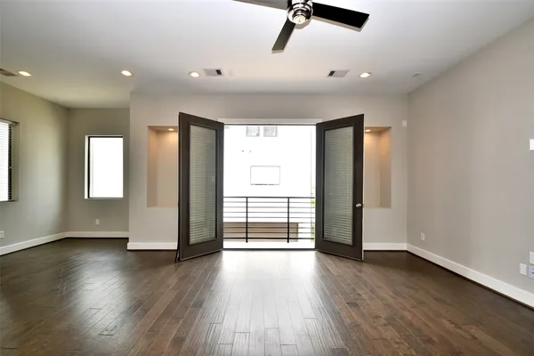 a view of empty room with wooden floor and fan