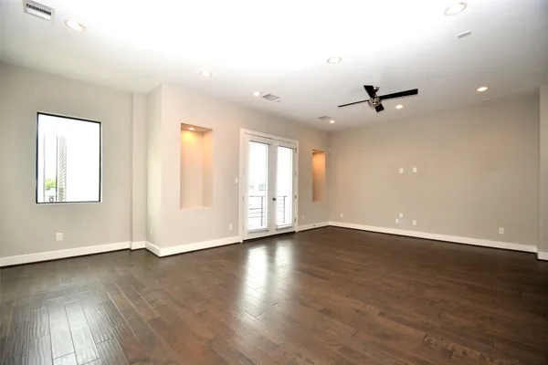 a view of an empty room with wooden floor and a window