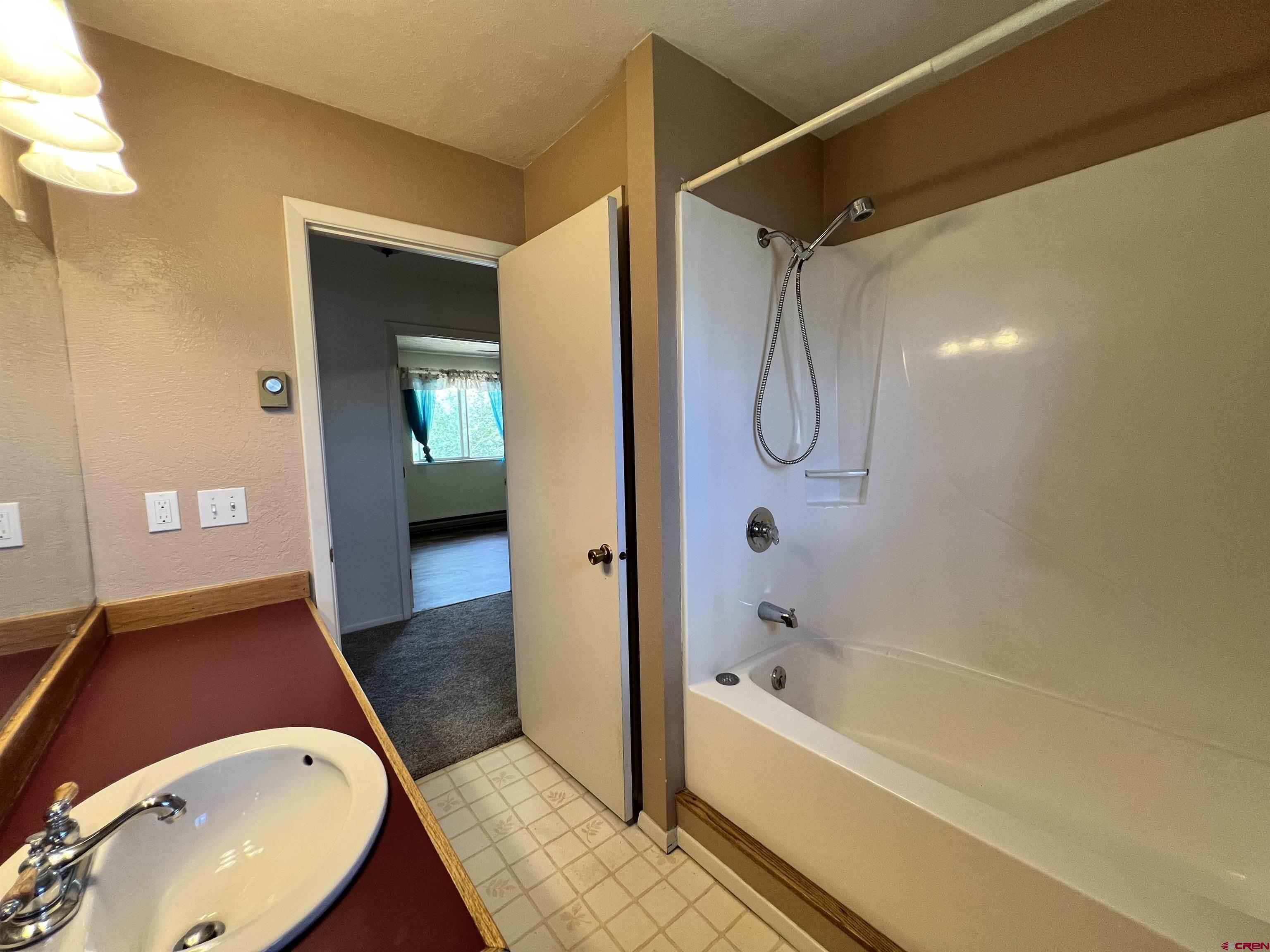 1328 Jackson Street Cortez, CO 81321 - Photo 19 of 37 a bathroom with a granite countertop tub shower and mirror