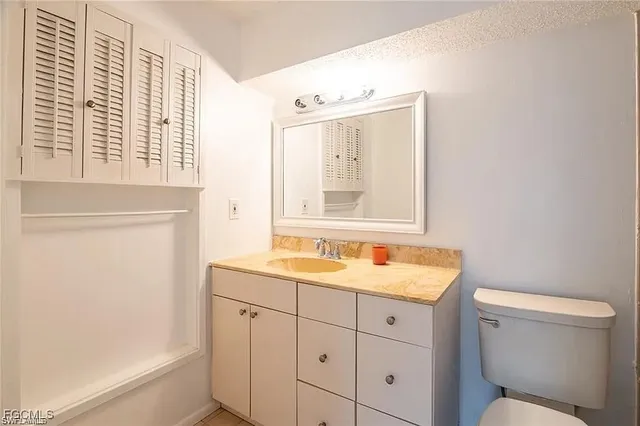 a bathroom with a granite countertop sink toilet and mirror