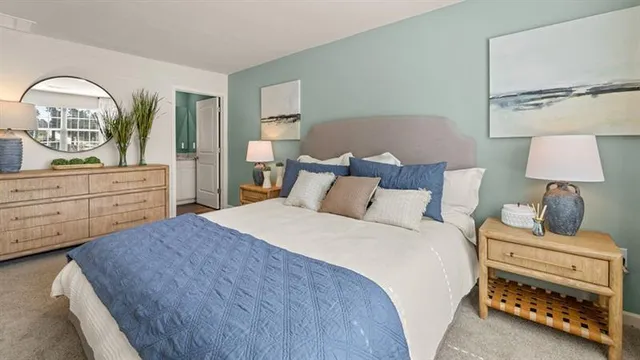 a bedroom with a bed and a lamp on dresser