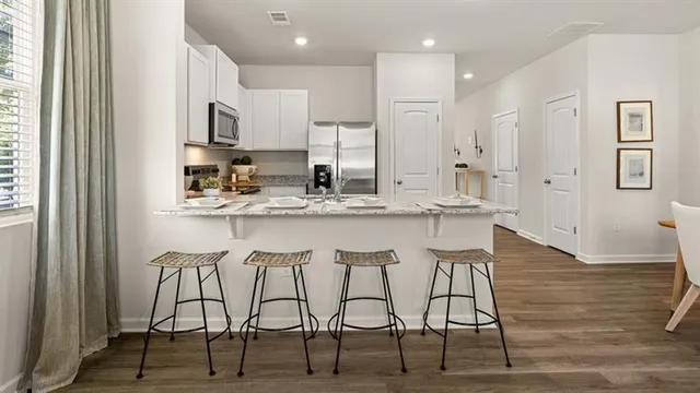 a kitchen with stainless steel appliances kitchen island granite countertop a table chairs sink and cabinets