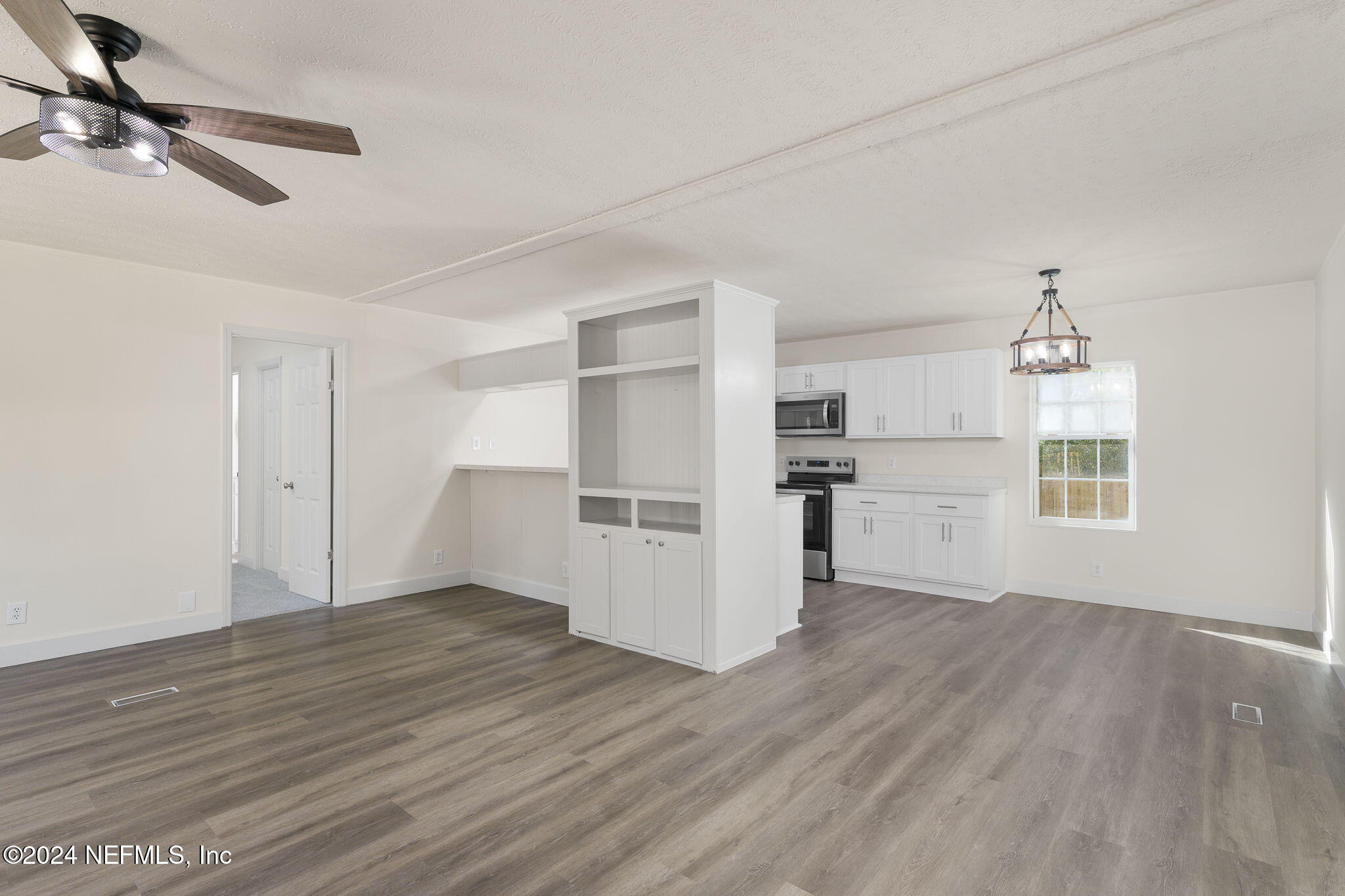 4526 Lambing Road Jacksonville, FL 32210 - Photo 6 of 32 an empty room with wooden floor kitchen view and windows