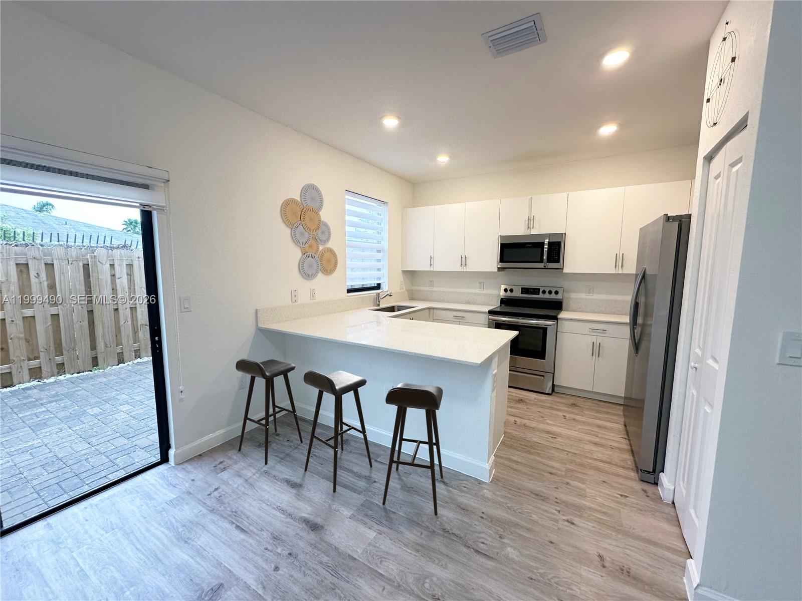 949 Northeast 211th Street Miami, FL 33179 - Photo 7 of 27 a kitchen with stainless steel appliances a refrigerator a stove a sink dishwasher and a stove with wooden floor