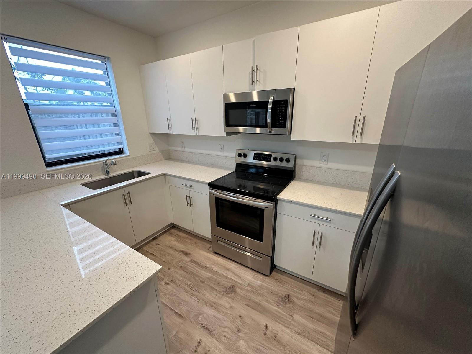 949 Northeast 211th Street Miami, FL 33179 - Photo 8 of 27 a kitchen with granite countertop a sink stove and microwave