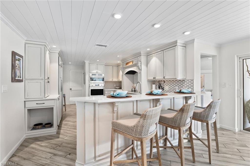 3737 Crayton Road Naples, FL 34103 - Photo 11 of 33 a kitchen with white cabinets and chairs