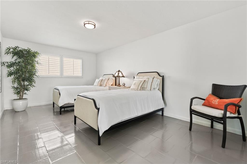3737 Crayton Road Naples, FL 34103 - Photo 23 of 33 a bedroom with a bed and a chair