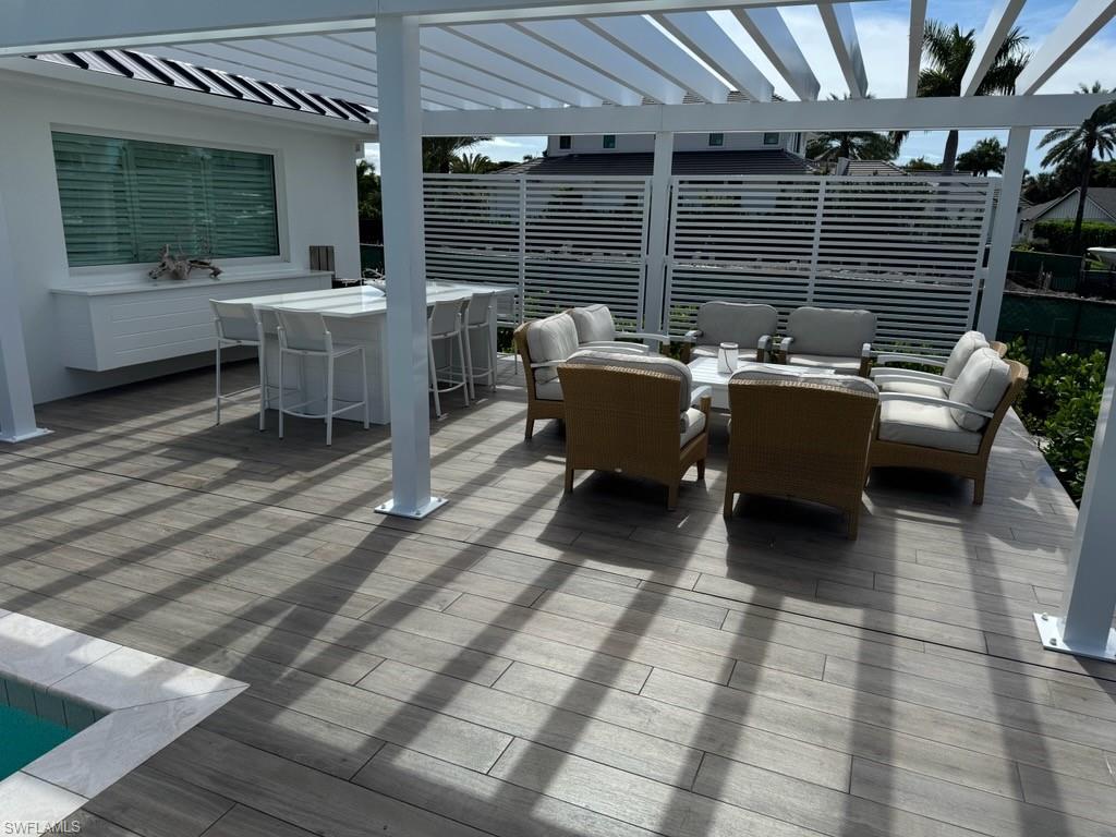 3737 Crayton Road Naples, FL 34103 - Photo 33 of 33 a view of a patio with couches table and chairs with wooden floor