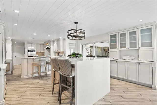 a living room with kitchen island stainless steel appliances furniture cabinets and a counter top space