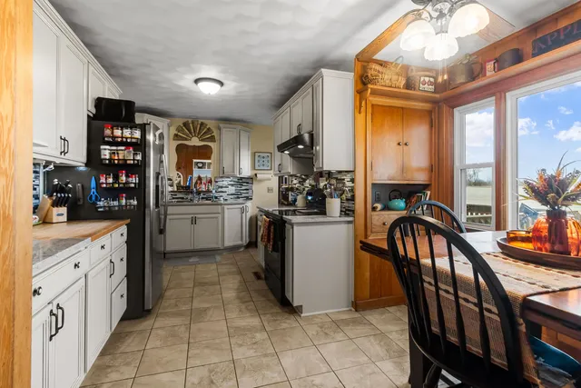 a kitchen with stainless steel appliances kitchen island granite countertop a table chairs in it and a sink