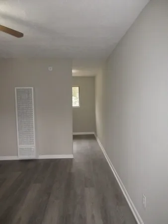 a view of an empty room with wooden floor and a window