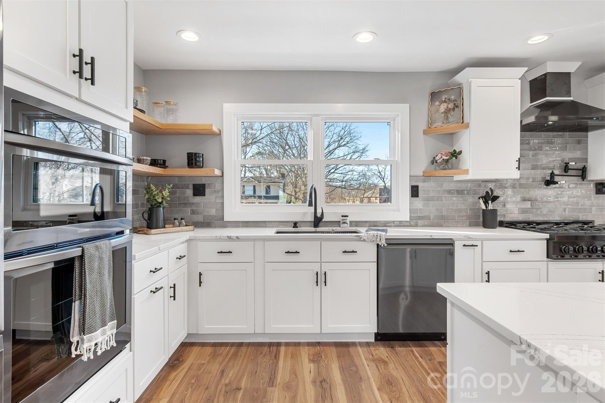 1206 9th Street Northwest Hickory, NC 28601 - Photo 11 of 40 a kitchen with stainless steel appliances granite countertop a stove a sink dishwasher and a refrigerator with wooden floor