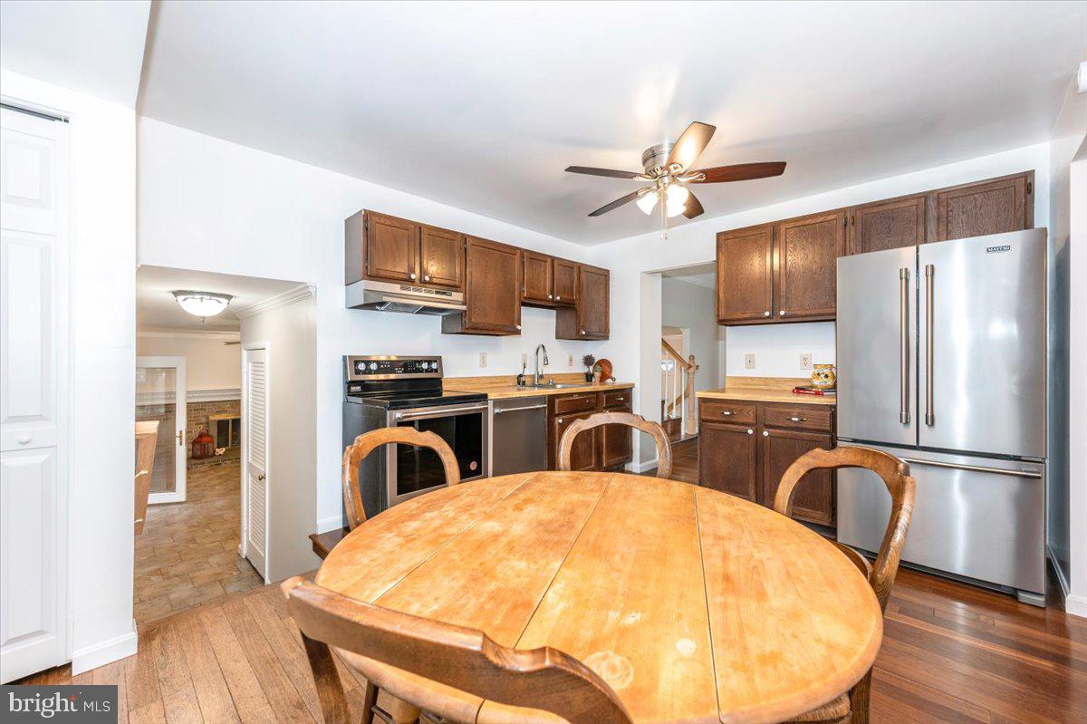 19924 Westerly Avenue Poolesville, MD 20837 - Photo 17 of 80 a kitchen with stainless steel appliances granite countertop a refrigerator a stove a sink dishwasher a dining table and chairs with wooden floor