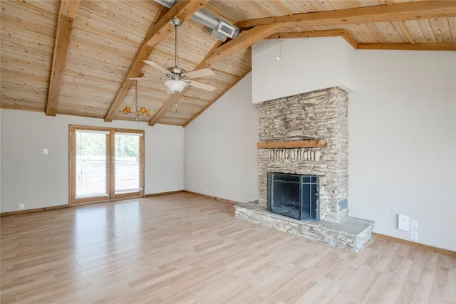 a view of an empty room with wooden floor fireplace and a window