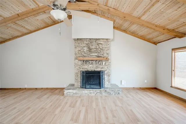 an empty room with wooden floor fireplace and windows