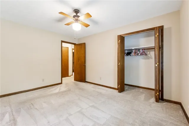 an empty room with closet and a chandelier fan