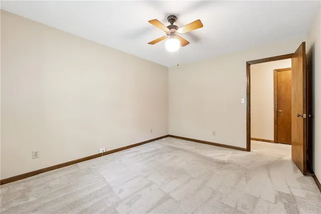 an empty room with closet and a ceiling fan