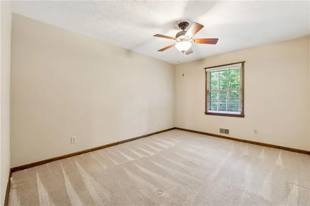 an empty room with window and ceiling fan