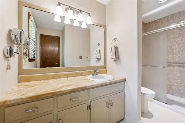 a bathroom with a granite countertop sink a toilet and a mirror