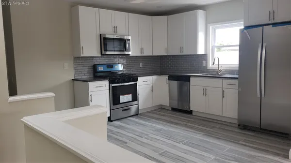 a kitchen with stainless steel appliances granite countertop a stove a sink and a microwave