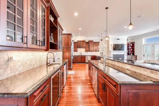 a large kitchen with stainless steel appliances kitchen island granite countertop a large counter top and a view of living room
