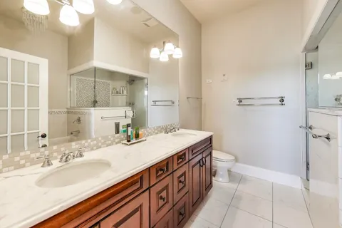 a bathroom with a granite countertop sink a toilet a mirror and shower