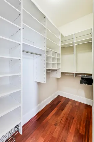 a view of an empty room with wooden floor and closet