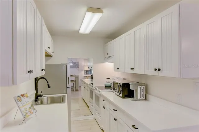 a kitchen with stainless steel appliances granite countertop a sink dishwasher and white cabinets with wooden floor