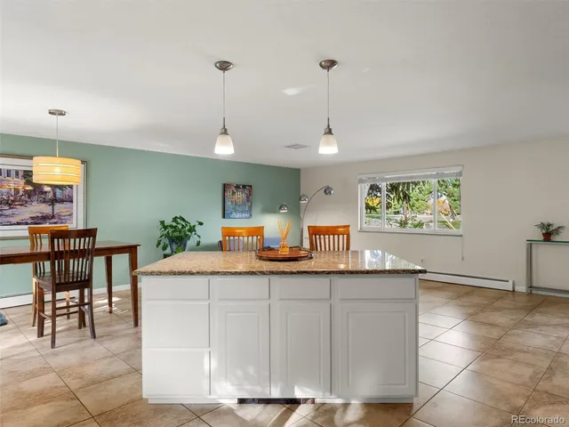 a kitchen with stainless steel appliances granite countertop a sink a stove a dining table and chairs