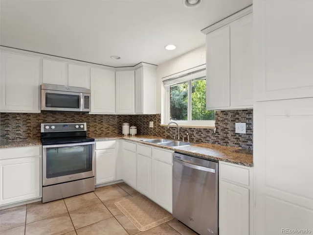 a kitchen with stainless steel appliances granite countertop a stove a sink and a microwave