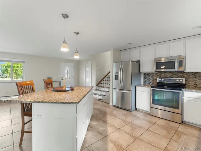 a kitchen with stainless steel appliances kitchen island a stove a sink a microwave a refrigerator and cabinets