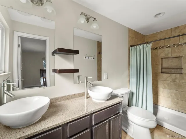 a bathroom with a granite countertop sink a toilet a mirror and shower