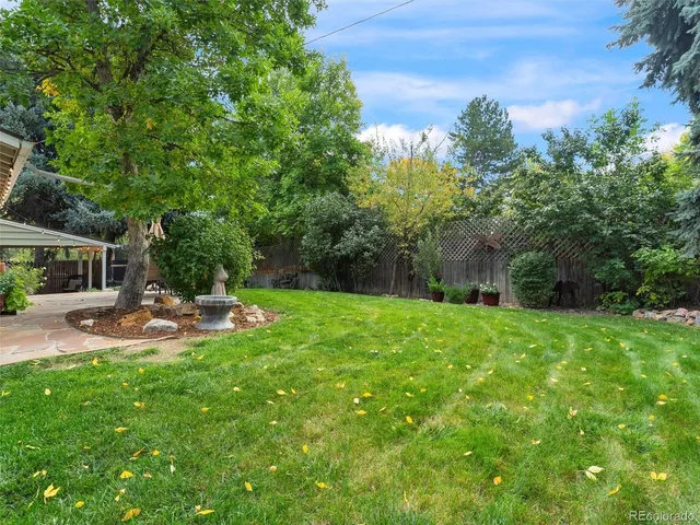 a view of a backyard with table and chairs and potted plants and large trees