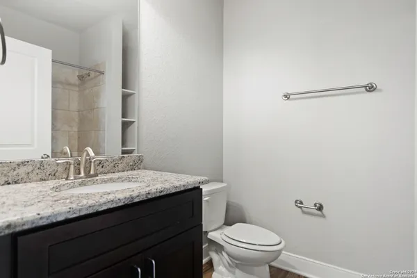 a bathroom with a granite countertop sink a toilet and a mirror