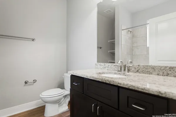 a bathroom with a granite countertop sink a toilet and a mirror