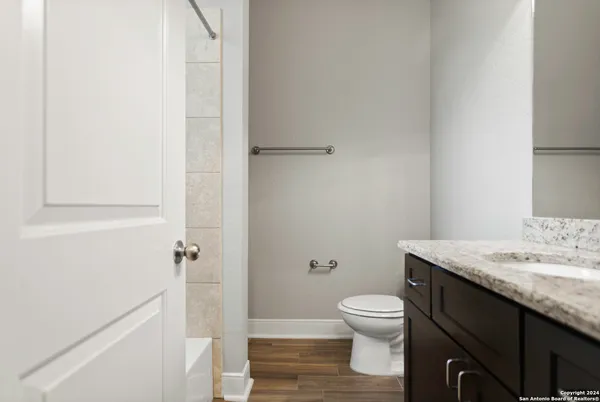 a bathroom with a granite countertop toilet a sink and a mirror