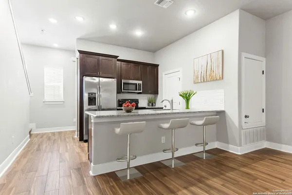 a kitchen with stainless steel appliances a sink cabinets and wooden floor