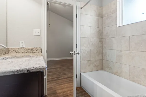 a bathroom with a granite countertop bathtub and shower