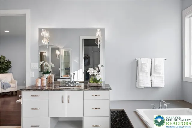 a view of a hallway with wooden floor and a bathroom