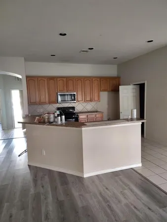a view of kitchen with stainless steel appliances granite countertop a stove top oven a sink dishwasher and wooden cabinets with wooden floor
