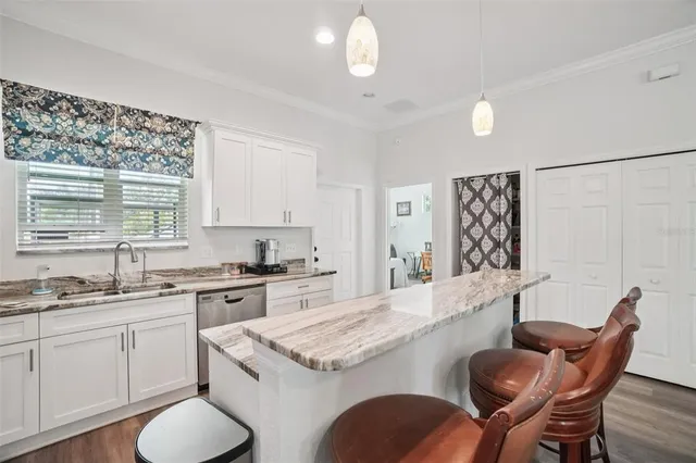 a kitchen with stainless steel appliances granite countertop a sink a stove a dining table and chairs