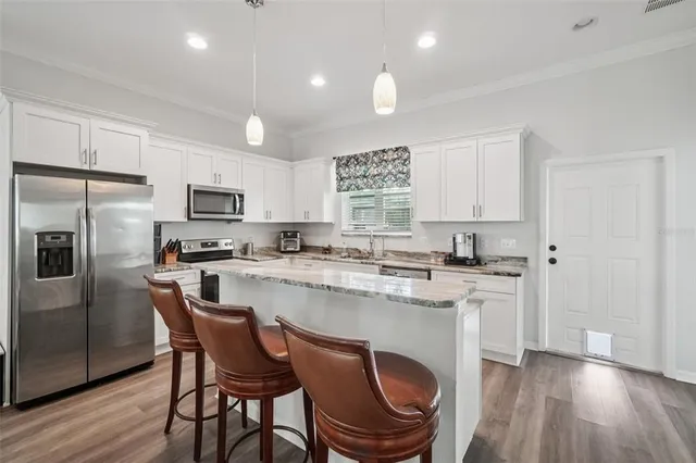 a kitchen with stainless steel appliances granite countertop a white cabinets and wooden floor