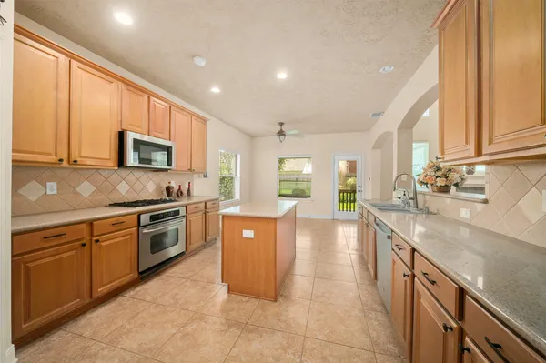 a large kitchen with granite countertop a stove top oven a sink a counter space and cabinets